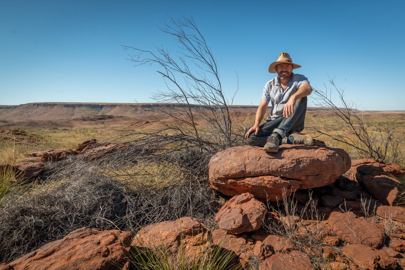 Luke Scholes seated on a rock outcrop at Lirrangani, Western Australia